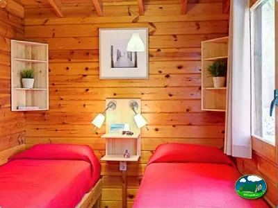 Cabaña interior con dos camas y paredes de madera del Camping Son Bou, Alaior (Menorca)