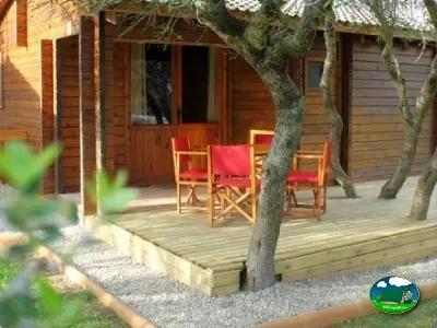 Bungalow de madera con terraza y sombra de árboles del Camping Son Bou, Alaior (Menorca)