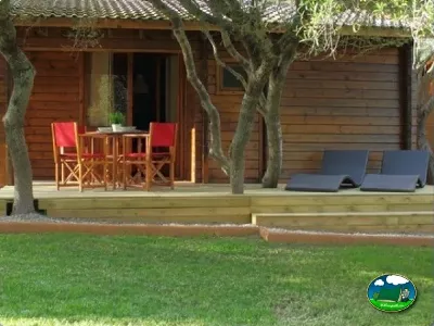 Bungalow con terraza y sombrilla, tumbonas y árboles del Camping Son Bou, Alaior (Menorca)