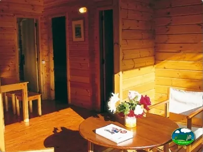 Cabaña de madera interior con cama y zona de estar del Camping Son Bou, Alaior (Menorca)