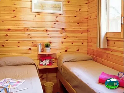 Cabaña interior con dos camas y paredes de madera del Camping Son Bou, Alaior (Menorca)