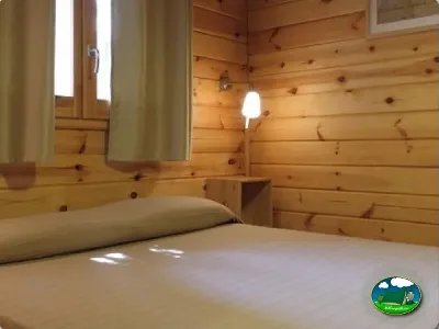 Cabaña interior con cama y paredes de madera del Camping Son Bou, Alaior (Menorca)
