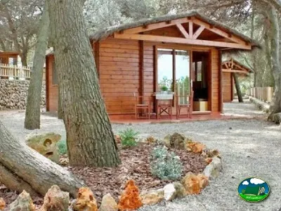 Cabaña de madera entre árboles con terraza del Camping Son Bou, Alaior (Menorca)