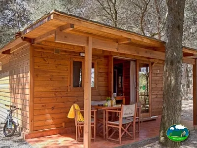 Cabaña de madera con terraza entre árboles del Camping Son Bou, Alaior (Menorca)