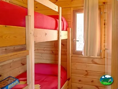 Cabaña interior con literas y camas rojas del Camping Son Bou, Alaior (Menorca)