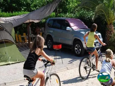 Parcela con tienda de acampada, vehículo y niños en bicicleta del Camping Bravoplaya, Ribera de cabanes (Castellón)