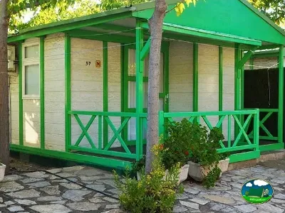 Cabaña con terraza cubierta y estructura verde del Camping Bravoplaya, Ribera de cabanes (Castellón)
