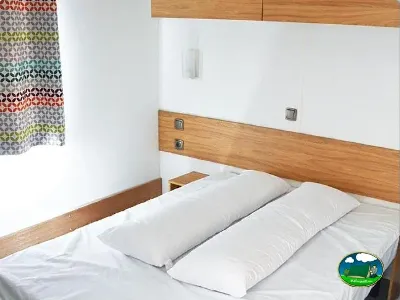 Mobil-home interior con cama doble y madera del Camping Bravoplaya, Ribera de cabanes (Castellón)