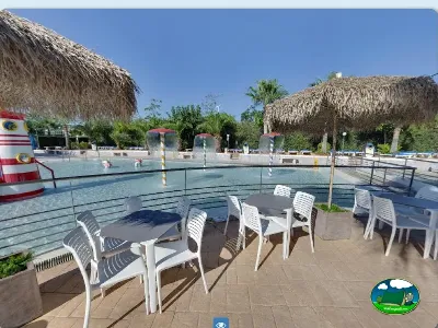 Piscina infantil con sombrillas de paja y zona de estar del Camping Bravoplaya, Ribera de cabanes (Castellón)