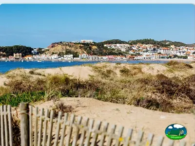 Playa junto al mar con pueblo costero y dunas del Camping Baía Azul, Alcobaça (Leiria)