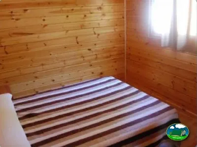 Cabaña interior con cama y paredes de madera del Camping La Torre del Sol, Montroig (Tarragona)