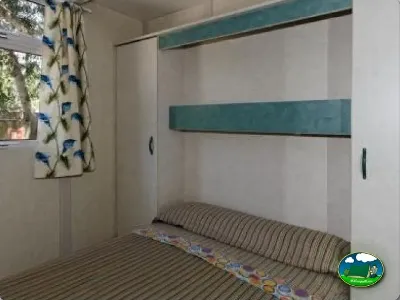 Mobil-home interior con cama y armarios del Camping La Torre del Sol, Montroig (Tarragona)