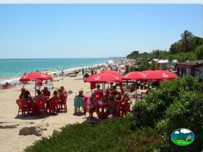 Playa junto al mar con sombrillas rojas y zona de baño del Camping La Torre del Sol, Montroig (Tarragona)