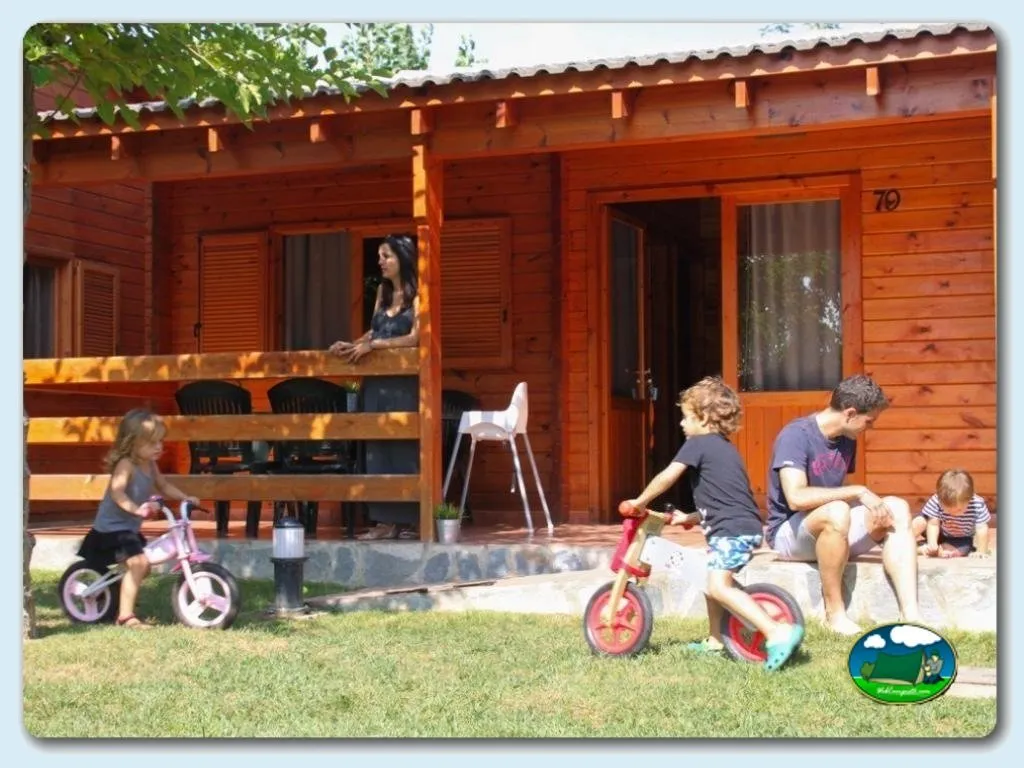 Cabaña de madera con familia y niños jugando en parcela del Camping Joan, Cambrils (Tarragona)