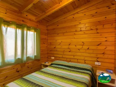 Cabaña de madera interior con cama y ventanas del Camping La Llosa, Cambrils (Tarragona)