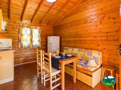 Cabaña de madera interior con cocina, comedor y sofá cama del Camping La Llosa, Cambrils (Tarragona)