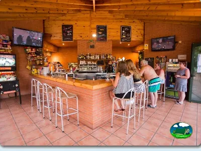 Restaurante bar con barra de madera y pantallas del Camping La Llosa, Cambrils (Tarragona)