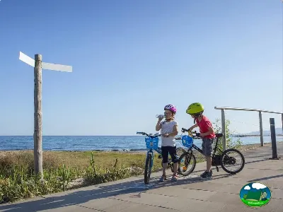 Niños en bicicleta junto al mar con paseo marítimo del Camping La Llosa, Cambrils (Tarragona)